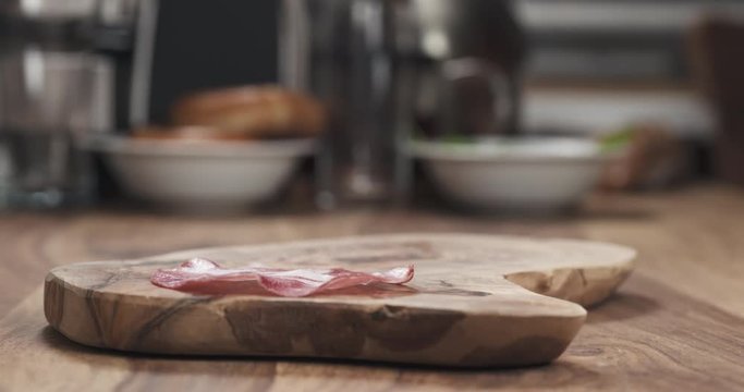 Slow motion of Italian coppa ham falling on wood board closeup