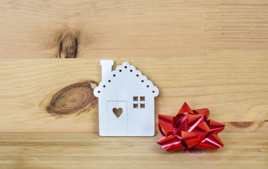 Small White House Model with Red Ribbon  On Wooden Background