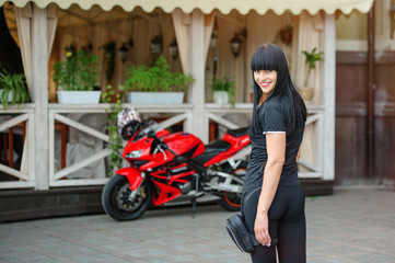 Fototapeta na wymiar Girl biker in black clothes on a sports motorcycle posing in the city