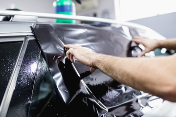 Car tinting - Worker applying tinting foil on car window. 