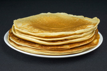stack of pancakes on a white plate black background, selective focus
