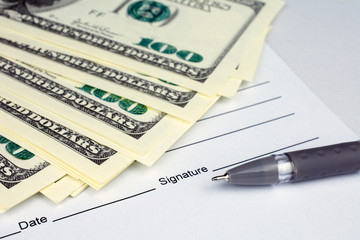 pen laying over a contract waiting to be signed money dollars