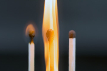 the flame of a burning match on a dark  blurred neutral background supplementary pension concept, close up,  selective focus