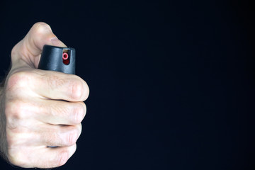 pepper gas in the hand of a young man in a black jacket CS spray self-defense Tear gas concept,...