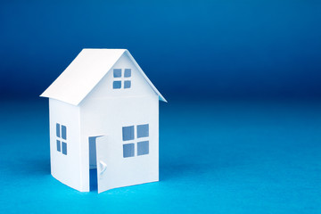 white small house on blue background, close up, selective focus Real Estate concept