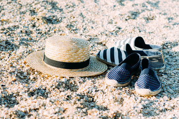 Straw hat and espadrilles lying on the sand on the beach. Summer concept. Holiday relaxing, beach...