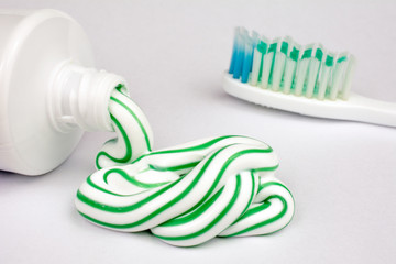 Green and white toothpaste squeezed out of a tube, toothbrush,  dental hygiene concept, close up, selective focus, white background