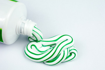 Green and white toothpaste squeezed out of a tube dental hygiene concept, close up, selective focus, white background