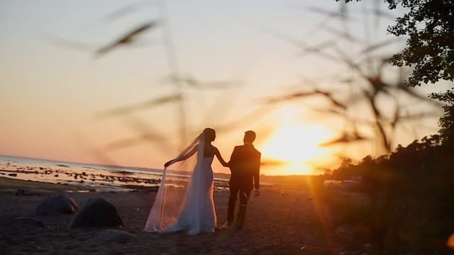 Bride and groom at the beach at sunset