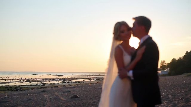 Bride and groom kissing at the beach at sunset