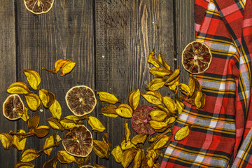 Cotton petals with dried lemons on a wooden background with checkered textiles. Place for text. Decorative background.