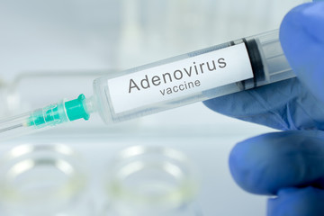 Fototapeta premium Vaccination healthcare concept. Hands of doctor or nurse in medical gloves with medical syringe ready for injection a shot of Adenovirus vaccine. close up, selective focus