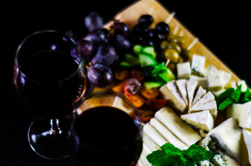 Red wine and set of different cheeses on a wooden board, delicious snack