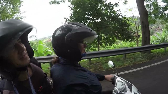 funny couple travelling on motorbike by asian green nature with jugle road, transportation in asia, left side traffic, happy vacation, tourism, travel concept, selfie, fun