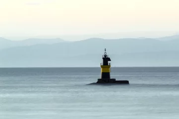 Wandcirkels aluminium lighthouse on the sea with mountains in the background © Jose Solis 
