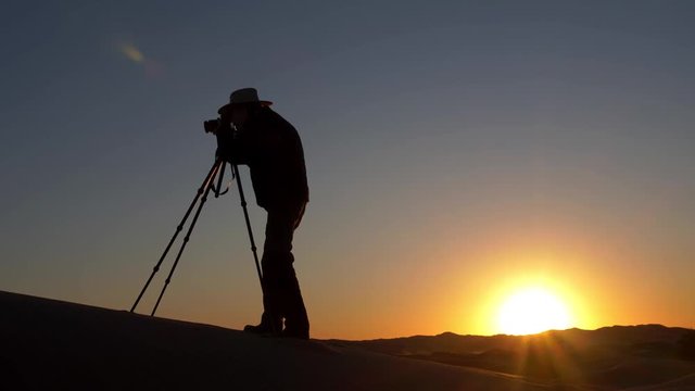 Silhouette of a man taking photos at sunset