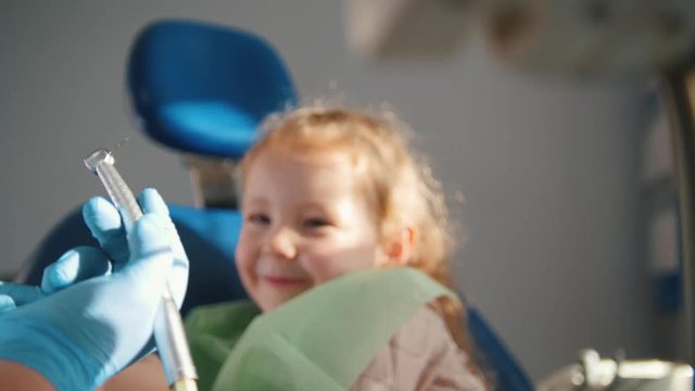 Little cute girl in the dentist's office does not want to be treated, resisting and closing her mouth with her hands