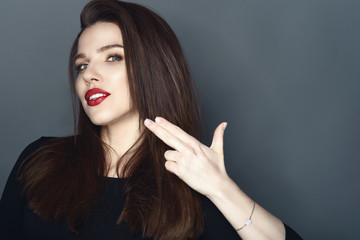 Portrait of beautiful smiling woman with perfect make up holding her fingers in the shape of the...