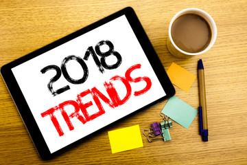 Handwritten text caption showing 2018 Trends. Business concept writing for Trending Data Prediction Written on tablet laptop, wooden background with sticky note, coffee and pen