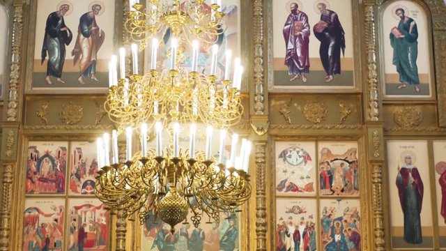 Russian orthodox church inside. Golden big chandelier close up and religious frescoes as background.