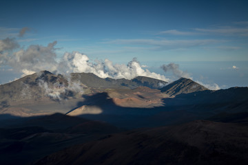 view taken from a high altitude at the summit of haleakala on the island of maui in hawaii in the pacific ocean showing the view down into the haleakala crater with shadows moving and clouds