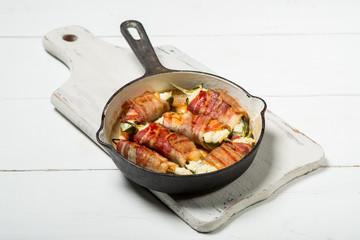 Vegetables and bacon meat roasted in pan. White wooden background, natural light