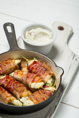 Vegetables and bacon meat roasted in pan. White wooden background, natural light