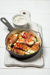 Vegetables and bacon meat roasted in pan. White wooden background, natural light