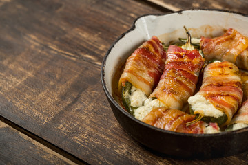 Hot spicy pepper  with cheese and bacon and baked iron pan. Rustic recipe food on wooden background.