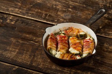 Hot spicy pepper - jalapeño stuffed with cheese and bacon and baked iron pan. Rustic recipe food on wooden background.