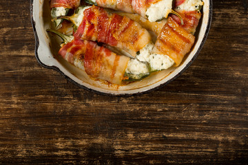 Hot spicy pepper - jalapeño stuffed with cheese and bacon and baked iron pan. Rustic recipe food on wooden background. Top view, flat lay.