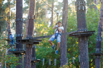 very cute and brave boy is in the adventure rope park. he will cope with all challenges!
