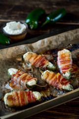Vegetables stuffed with cheese and bacon and baked on tray in oven. Rustic recipe food on wooden background. Top view