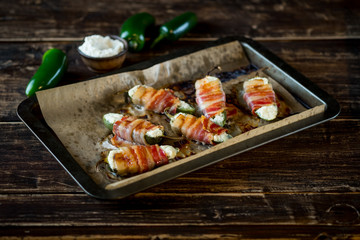 Vegetables stuffed with cheese and bacon and baked on tray in oven. Rustic recipe food on wooden background. Top view