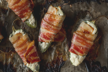 Vegetables stuffed with cheese and bacon and baked on tray in oven. Rustic recipe food on wooden background. Top view