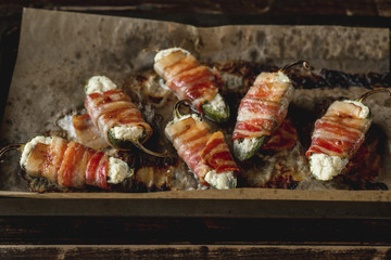 Vegetables stuffed with cheese and bacon and baked on tray in oven. Rustic recipe food on wooden background. Top view