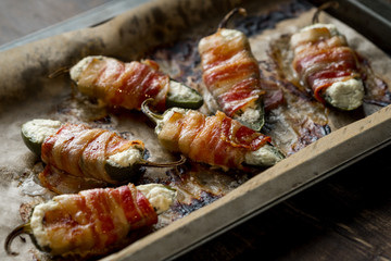 Vegetables stuffed with cheese and bacon and baked on tray in oven. Rustic recipe food on wooden background. Top view