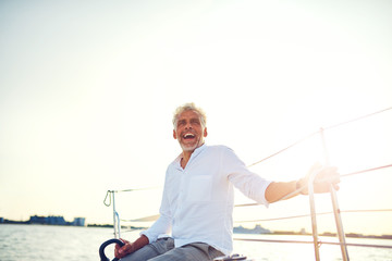 Laughing mature man enjoying a day sailing his yacht
