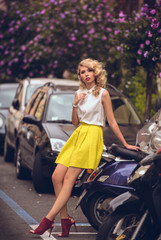 Fototapeta na wymiar Vogue style elegant portrait of beautiful fashion woman wavy shine blonde long hair. Model in summer hat yellow skirt red shoes with bright makeup walking at Rome Italy street and looking at camera