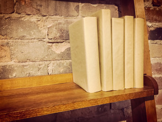 Books in paper covers on a wooden shelf