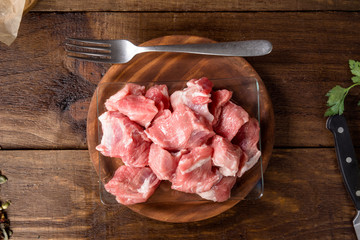 overhead take of pieces of uncooked pork, on rustic wood stage