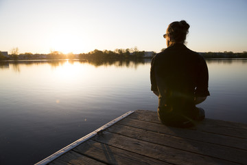 Man sits on a dock looking over still water