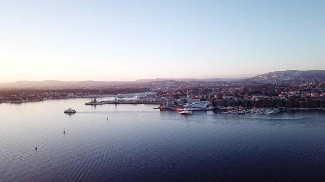 Aerial shot of two ferry boats in Oslo fjord, Norway, moving away from camera towards the sunset
