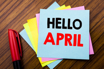 Handwriting Announcement text Hello April.  Concept for Spring Welcome Written on sticky stick note paper with wooden background with space office view with pencil marker