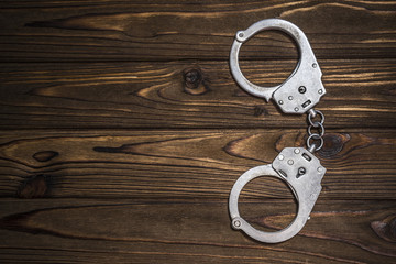 steel handcuffs on a wooden table with copy space. The idea of crime and punishment, the attacker,...
