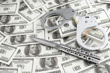 knife, handcuffs, against the background of dollar bills. robbery. law violation. crime of a corner.