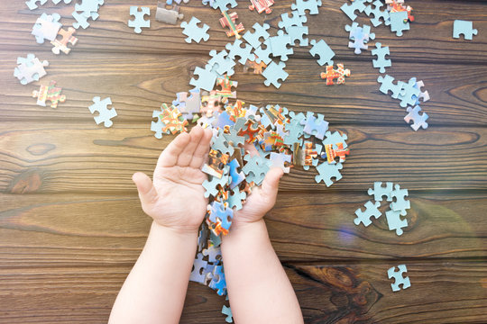 puzzles in the hands of a child on a wooden background. logical game. puzzle. pre-school education.