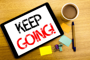 Handwritten text caption showing Keep Going. Business concept writing for Go Moving Forward Letting Written on tablet laptop, wooden background with sticky note, coffee and pen