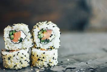 Japanese sushi roll philadelphia on black stone. Selective focus. Blurred foreground and background. Concrete grey background