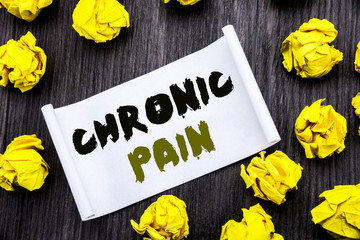Fototapeta premium Writing text showing Chronic Pain. Business concept for Feeling Bad ill Care Written on sticky note notepad note notebook book wooden background with yellow sticky folded.